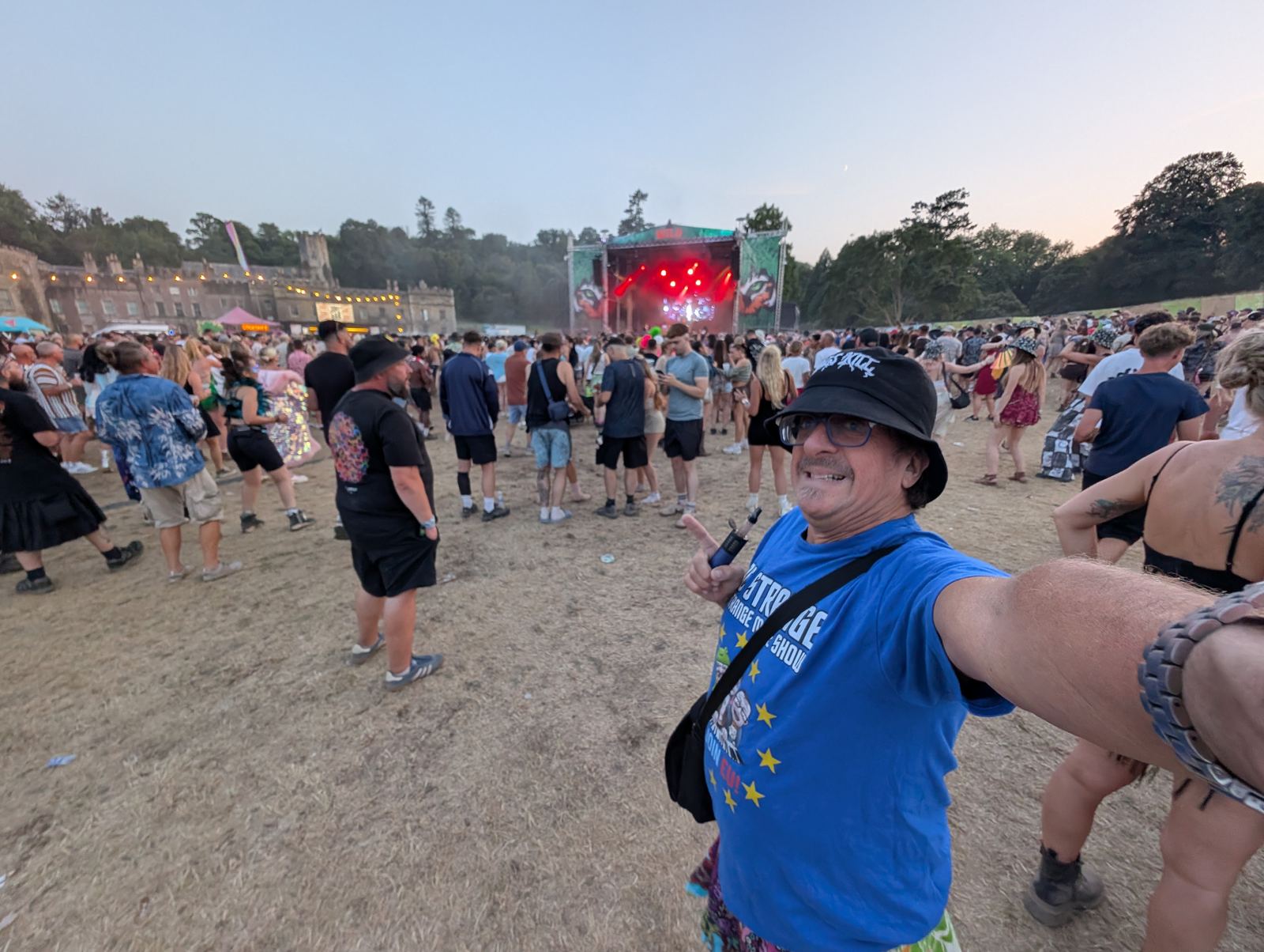 Doc at a festival main stage in daytime, castle in the background
